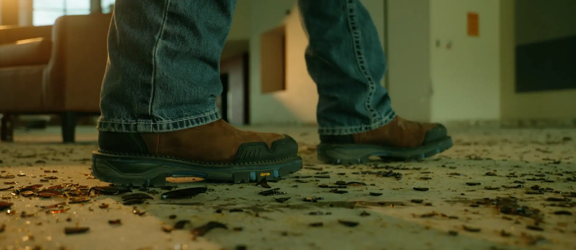 Work boots stepping through broken glass