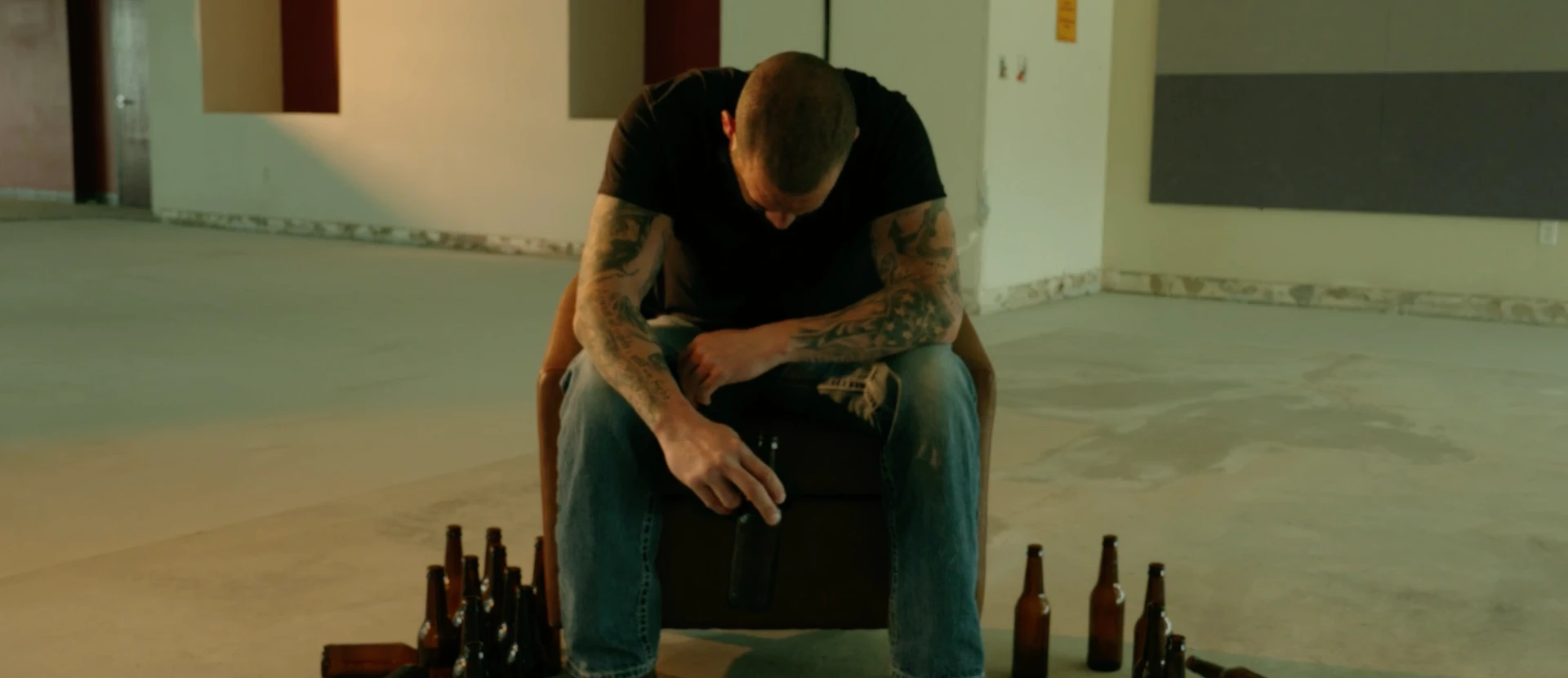 Jeff seated with his head down, surrounded by empty bottles